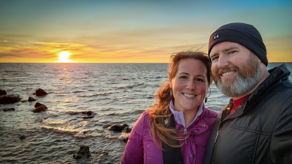 Captainn Tom and First Mate Elyse next to a sunset over the water.