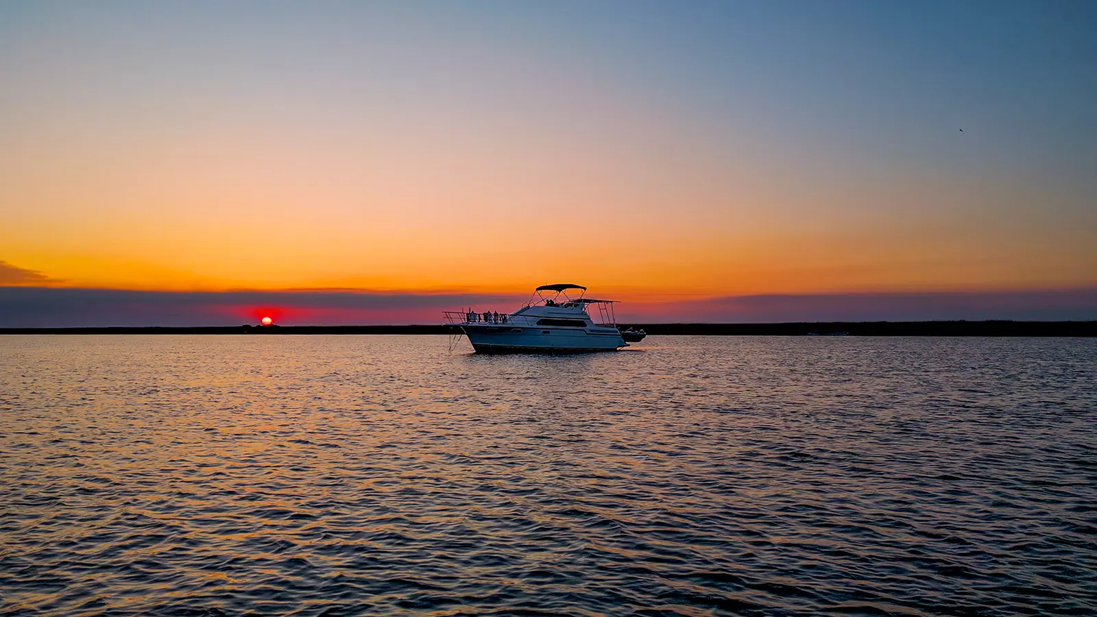Swamp Puppy anchored next to a red setting sun.