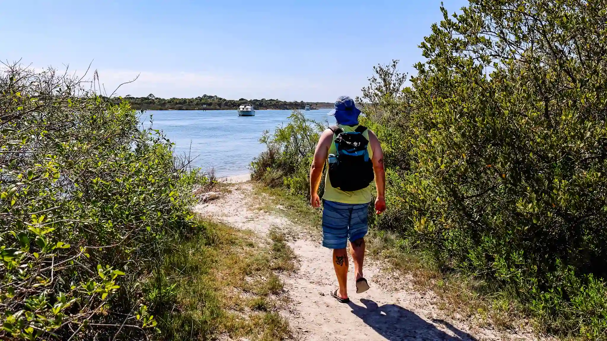 Tom walking a sandy trail and Swamp Puppy anchored out in the distance.