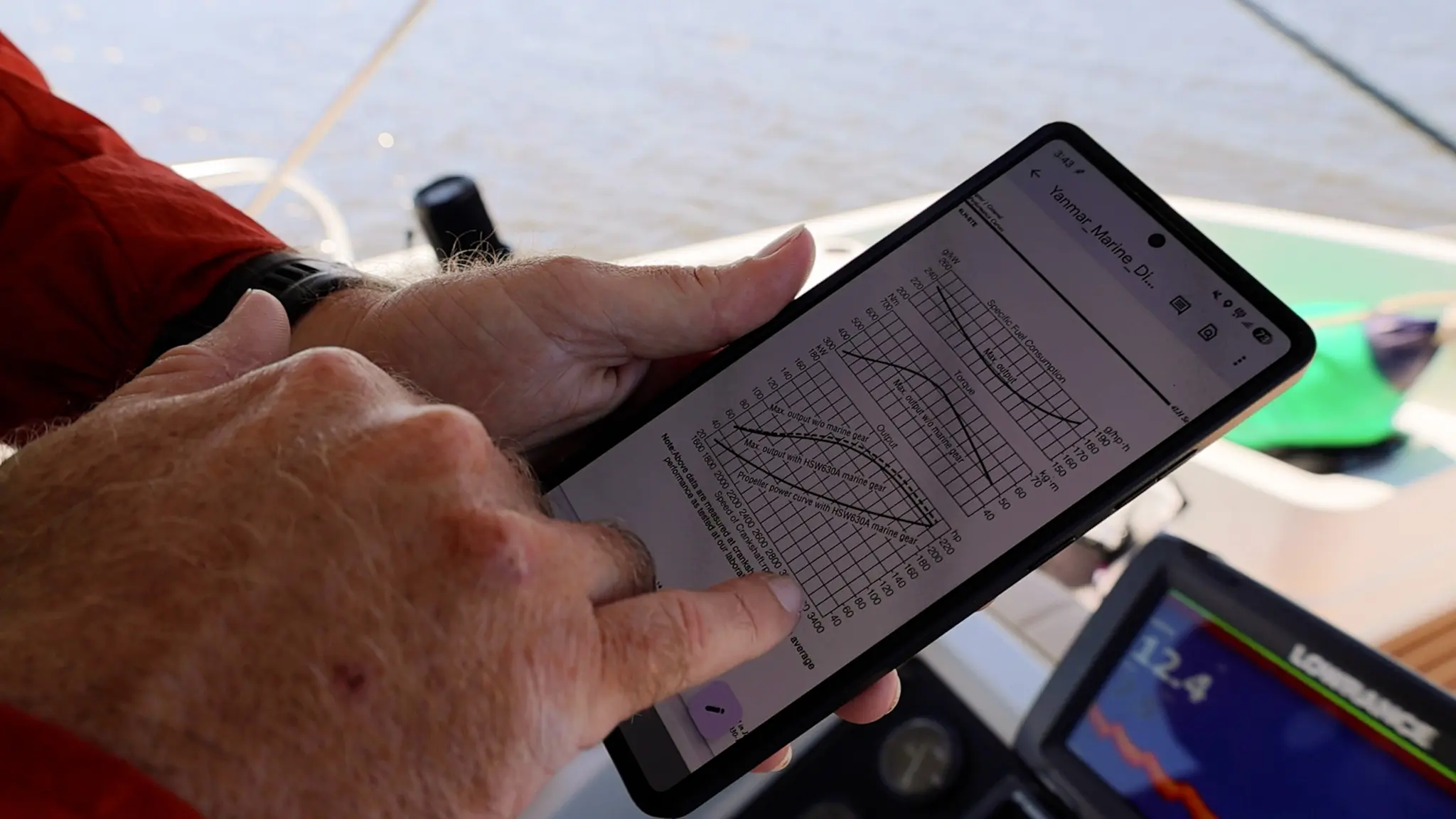 Captain Tom showing the Yanmar Specific Fuel Consumption graph on his phone.